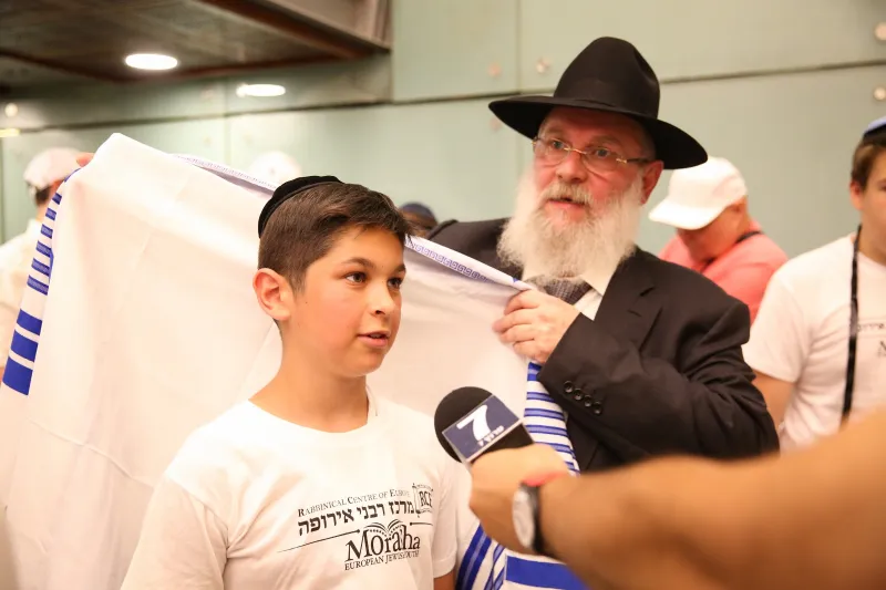 מנכל מרכז רבני אירופה עוטף את אחד מחתני הבר מצווה בטלית